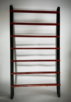 an old wooden book shelf with red and black strips on the bottom, against a white wall