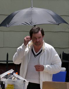 a man holding an umbrella over his head while standing next to a box and other items