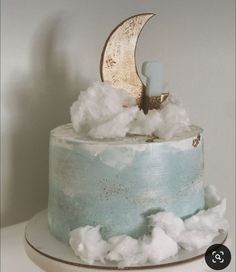 there is a blue cake with white frosting and a half moon on top