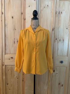 "1 mustard color  6 button front closure  Button cuff Collar  100% polyester  Chart size 8/medium  1 Rust color  Pullover  Collar  100% nylon  Chart size 10/medium  Sleeve and blouse length 23\" for both blouses  Both are in excellent vintage condition" Cheap Yellow Vintage Blouse, Gold Long Sleeve Tops With Button Cuffs, Gold Blouse With Buttons For Work, Gold Button-up Blouse With Button Closure, Mustard Long Sleeve Blouse For Fall, Yellow Fall Blouse For Daywear, Yellow Fall Daywear Blouse, Vintage Solid Color Blouse For Daywear, Retro Mustard Long Sleeve Tops