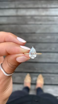 a woman's hand holding an engagement ring with a diamond on the middle finger