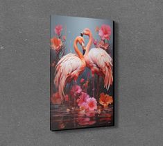 two flamingos standing next to each other in water with flowers on the wall behind them