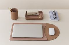 a desk with a laptop, mouse pad and glasses on it next to a cup