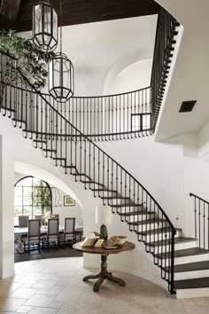 a spiral staircase in a home with black and white decor on the walls, along with a round dining table