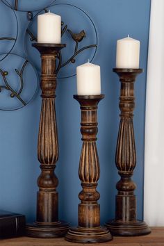 three wooden candlesticks on a table in front of a blue wall