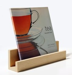 a cup of tea sitting on top of a wooden stand next to a magazine holder