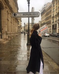 a woman is standing on the street reading a newspaper