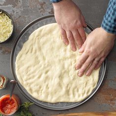 a person kneading dough on top of a metal pan next to other ingredients