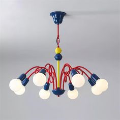 a blue and yellow chandelier hanging from the ceiling with red cords attached to it