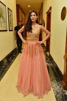 a woman standing in a hallway wearing a pink and gold dress with flowers on it