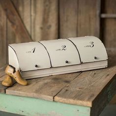 three white mailboxes sitting on top of a wooden table next to a pair of shoes