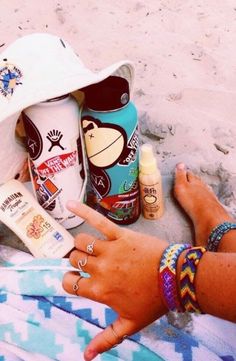 a person laying on the beach with sunscreen and other items