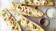 several pieces of bread with sauce and garnishes on them next to a small bowl