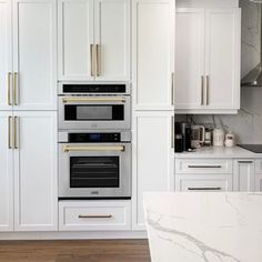 a kitchen with marble counter tops and white cabinets, two ovens are built into the wall