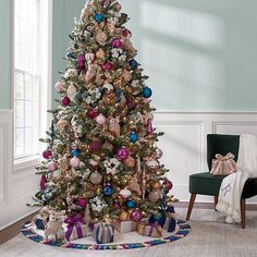 a decorated christmas tree in a living room with blue walls and white trimmings