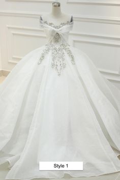 a white wedding dress on display in front of a mannequin headdress