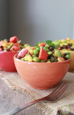 two bowls filled with vegetables on top of a table next to a knife and fork