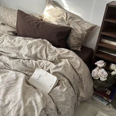 an unmade bed with flowers and books on it