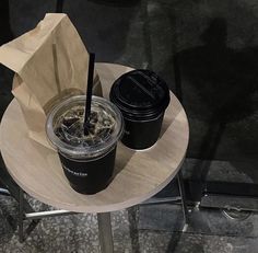 two drinks sitting on top of a wooden table next to a brown paper bag and some chairs