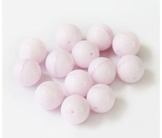 some pink balls are on a white surface and there is no image in the top right corner