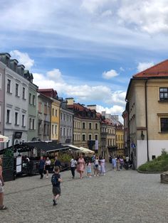 many people are walking around in an old town square with cobblestone streets and buildings