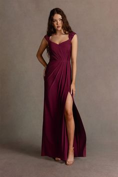 a woman in a long purple dress posing for the camera with her legs slited