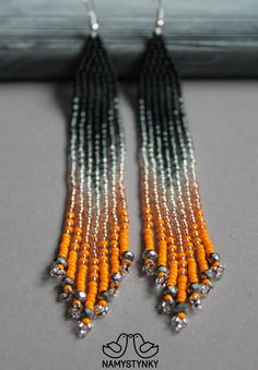 an orange and black beaded earrings with silver beads hanging from the end of it