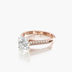 a rose gold engagement ring with diamonds on the band and an oval cut diamond in the center