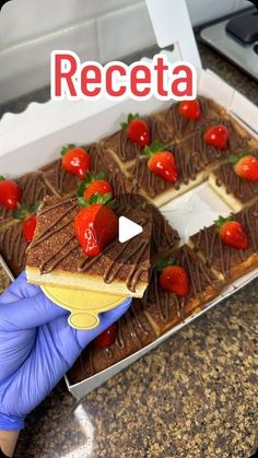 a person in blue gloves holds up a piece of cake with chocolate and strawberries on it