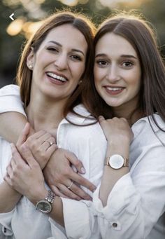 two young women are hugging each other in the middle of an outdoor photo taken at sunset