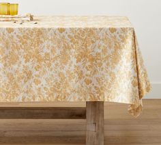 the table is covered with a yellow and white damask cloth, which has been placed on top of a wooden bench