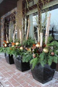 three black planters filled with evergreen and gold ornaments