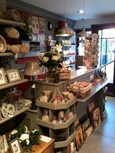 the inside of a store with lots of items on shelves and flowers in vases