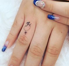 a woman's hand with blue fingernails and a cross tattoo on the middle finger