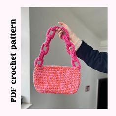 a person holding up a pink purse made out of crocheted yarn and plastic beads