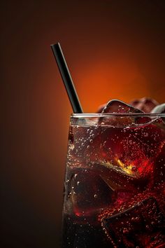 a glass with ice and strawberries in it on a dark surface next to an orange background