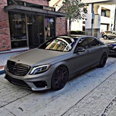 a silver car parked in front of a building on the side of a street next to another car