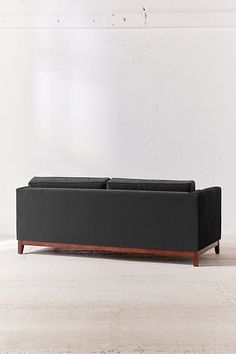 a black couch sitting on top of a hard wood floor