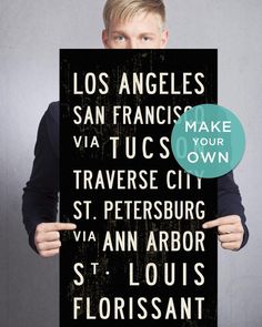 a man holding up a sign that reads los angeles, san francisco, tuscon, traverse city, st petersburg, and ann arbor st louis floris