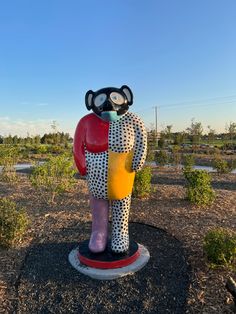 a statue of a bear holding a star in the middle of a field with trees and bushes