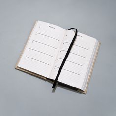 an open notebook with a black string attached to the front and back pages, on a gray surface