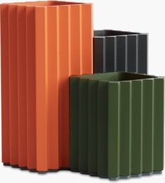 three different colored vases sitting next to each other on a white surface and one is orange, the other green