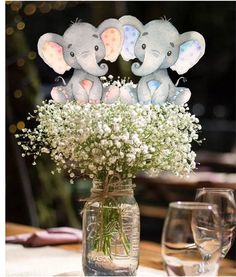 three elephants are sitting on top of a vase with baby's breath in it