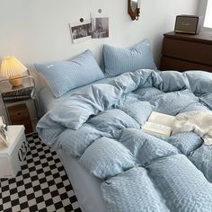 an unmade bed with blue sheets and pillows on top of it in a bedroom