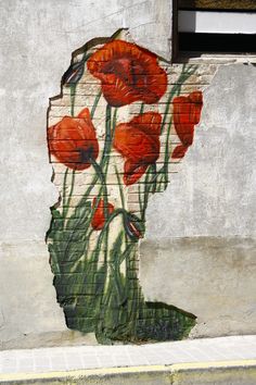 a painting on the side of a building with red flowers painted on it's side