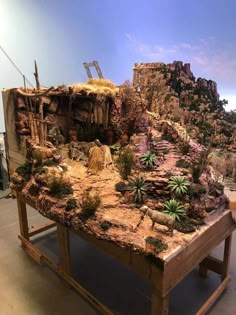 a table with plants and rocks on it in front of a blue wall that has a mountain behind it