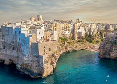 an aerial view of a city on the edge of a body of water with cliffs in the foreground