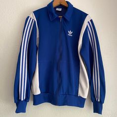 Hella cool Adidas trefoil track jacket. I am such a huge fan of Adidas and have a grand collection myself. The best I can discern this piece is from the 1990s, possibly 80s but the lining strikes me as more modern. The outer fabric is not the silky kind, it's the other kind. Anyway... Condition is flawless. Tag size is medium. Measurements, flat: Shoulder, 18" Underarm, 22.5" Waistband, 16.5",up to 20" Sleeve, from underarm, 20" Throwback Long Sleeve Track Jacket For College, Retro Fall Track Jacket For Streetwear, Retro Track Jacket With Ribbed Cuffs For Streetwear, Retro Streetwear Track Jacket With Ribbed Cuffs, Retro Track Jacket For College In Winter, Retro Track Jacket For Winter College Wear, Retro Winter Track Jacket For College, Vintage Long Sleeve Track Jacket For Winter, Retro Cotton Track Jacket For Streetwear