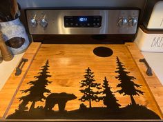 a cutting board with an image of a bear and trees on it in front of the stove