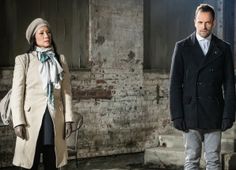 two people standing in an old building with brick walls and peeling paint on the walls